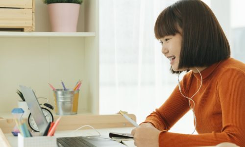 Beautiful young asian thai black short hair woman learning from home study online on laptop and wearing earphone.